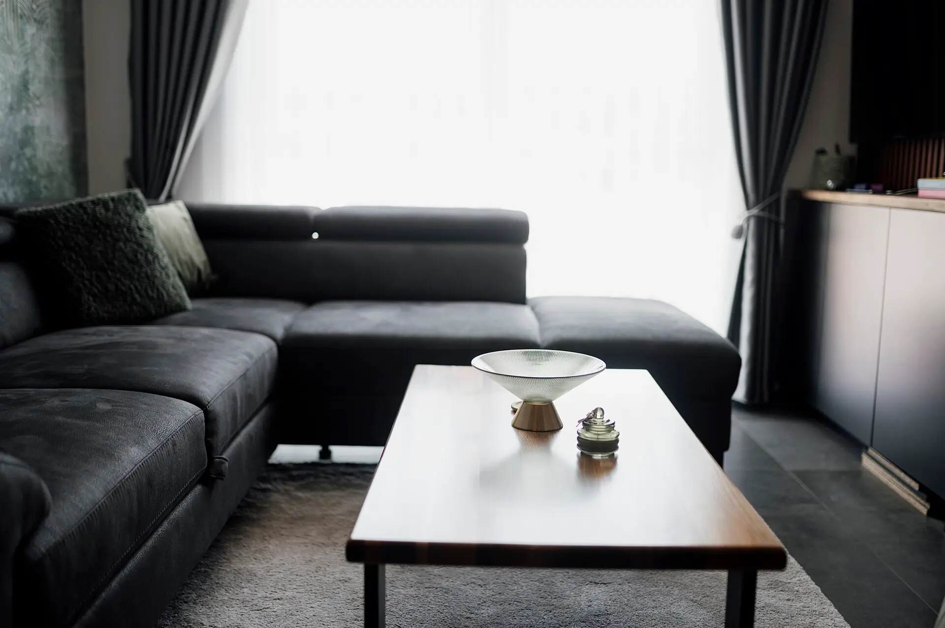 Living room with long curtains drawn beside a large window