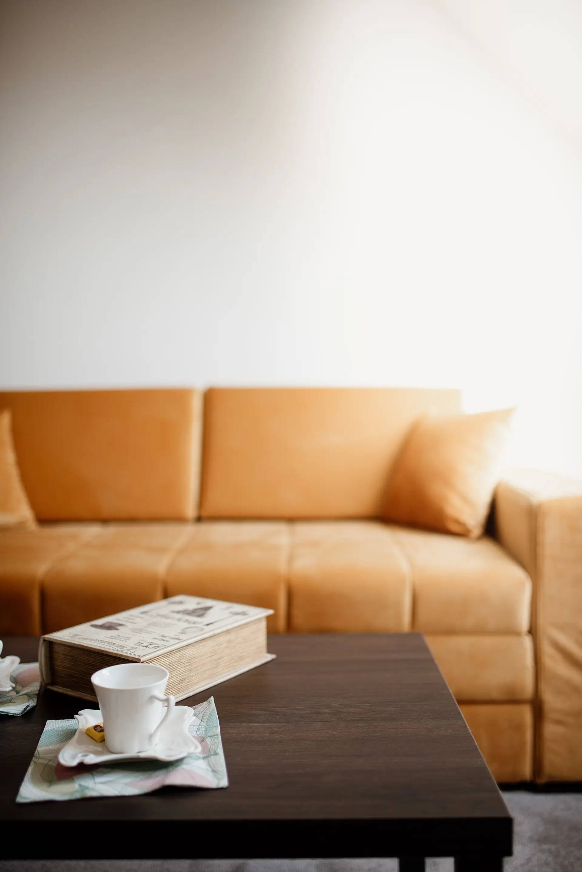 An orange sofa and coffee table with a cup and an open book