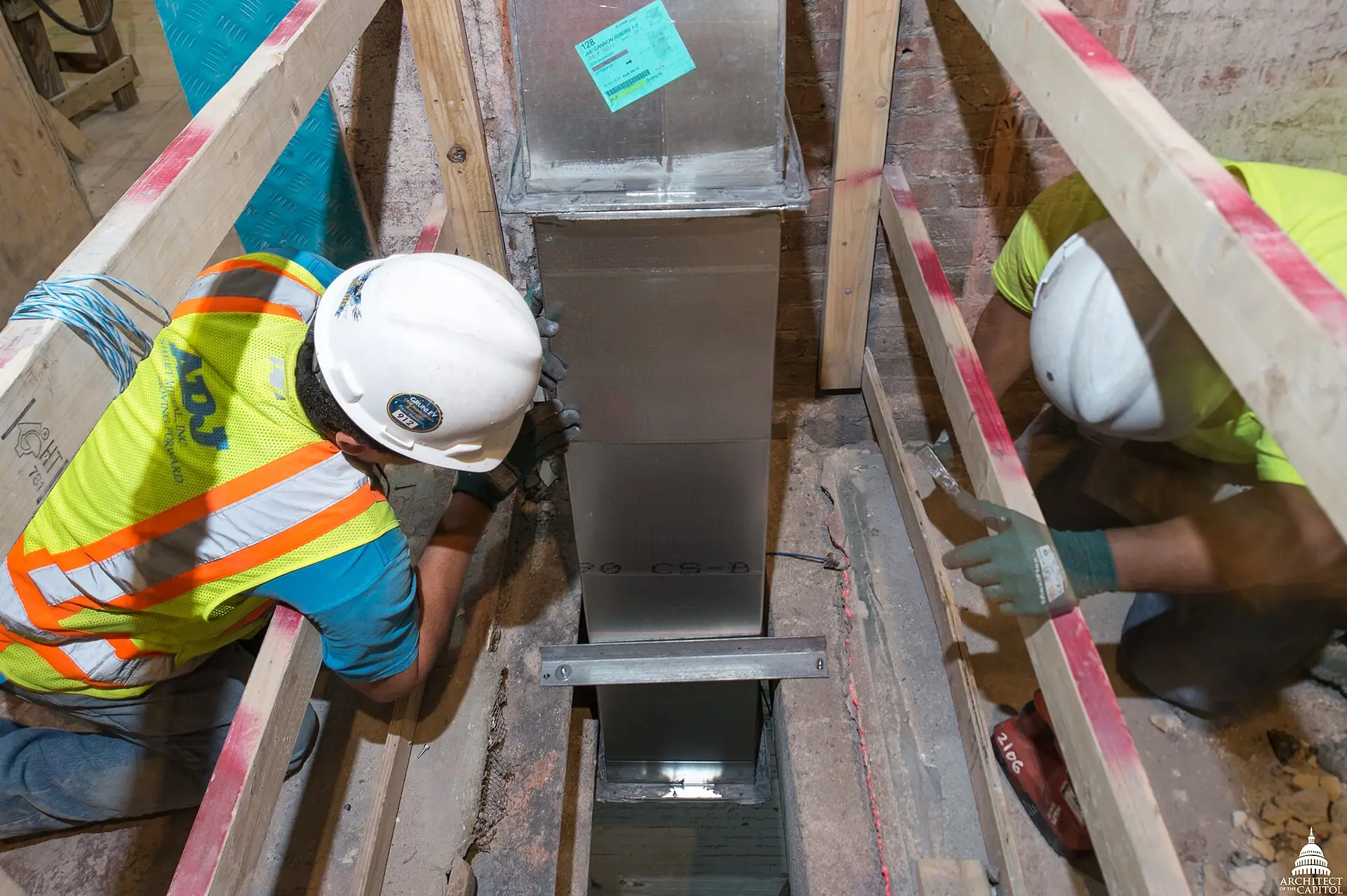 Workers installing a section of sheet-metal ductwork