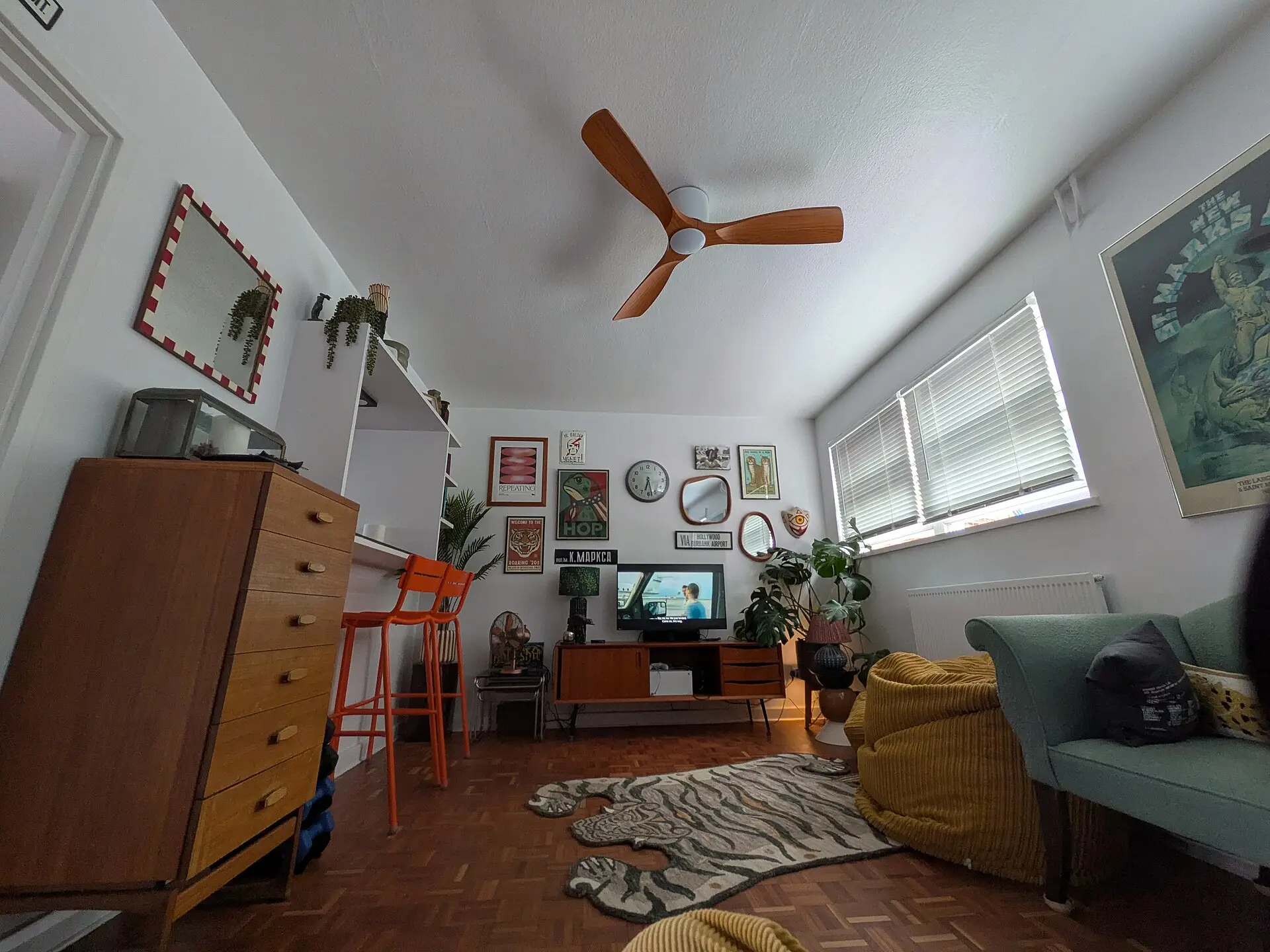 A sitting room with a ceiling fan, sofa and dresser