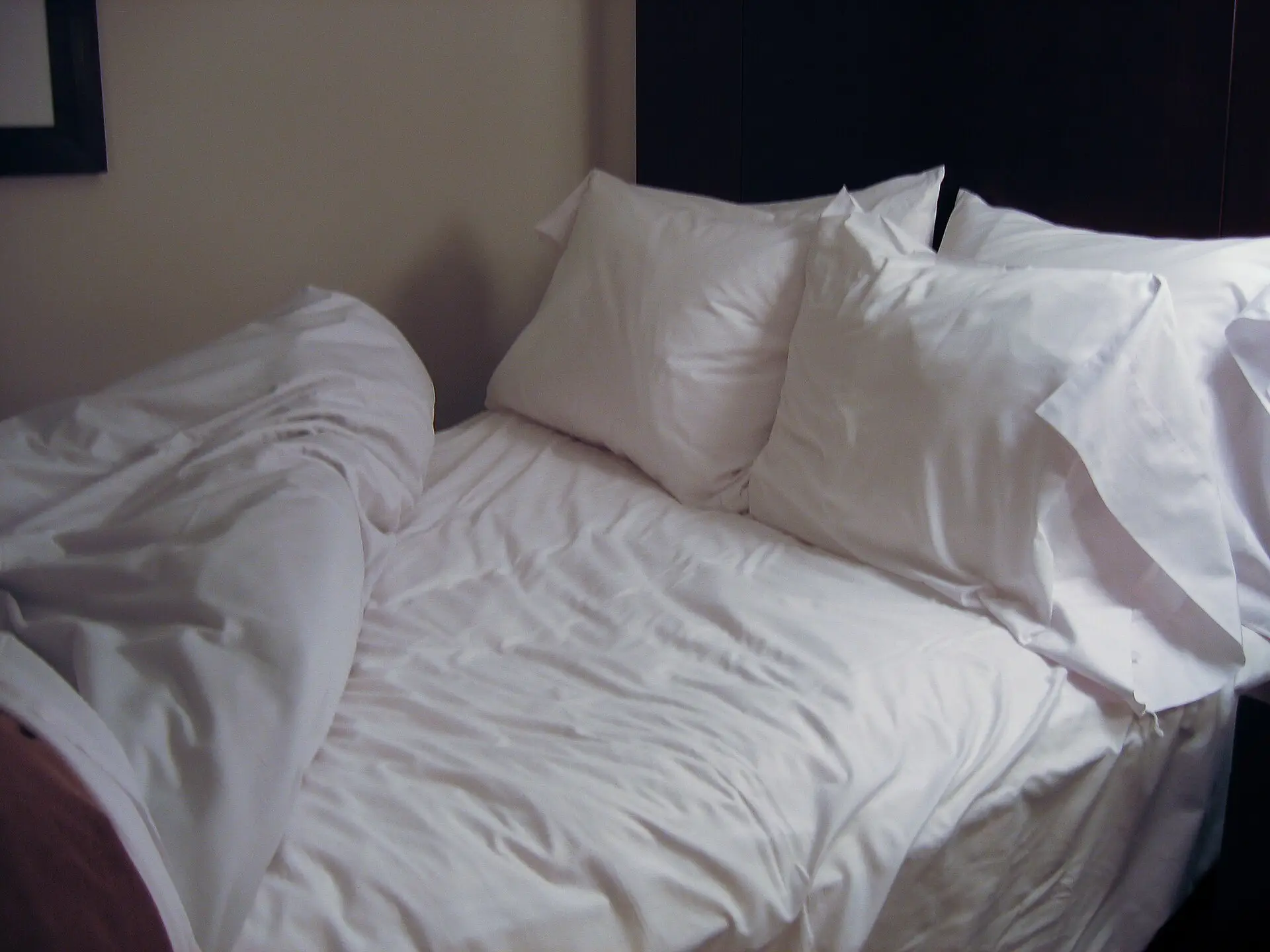 A neatly made bed with white sheets and pillows