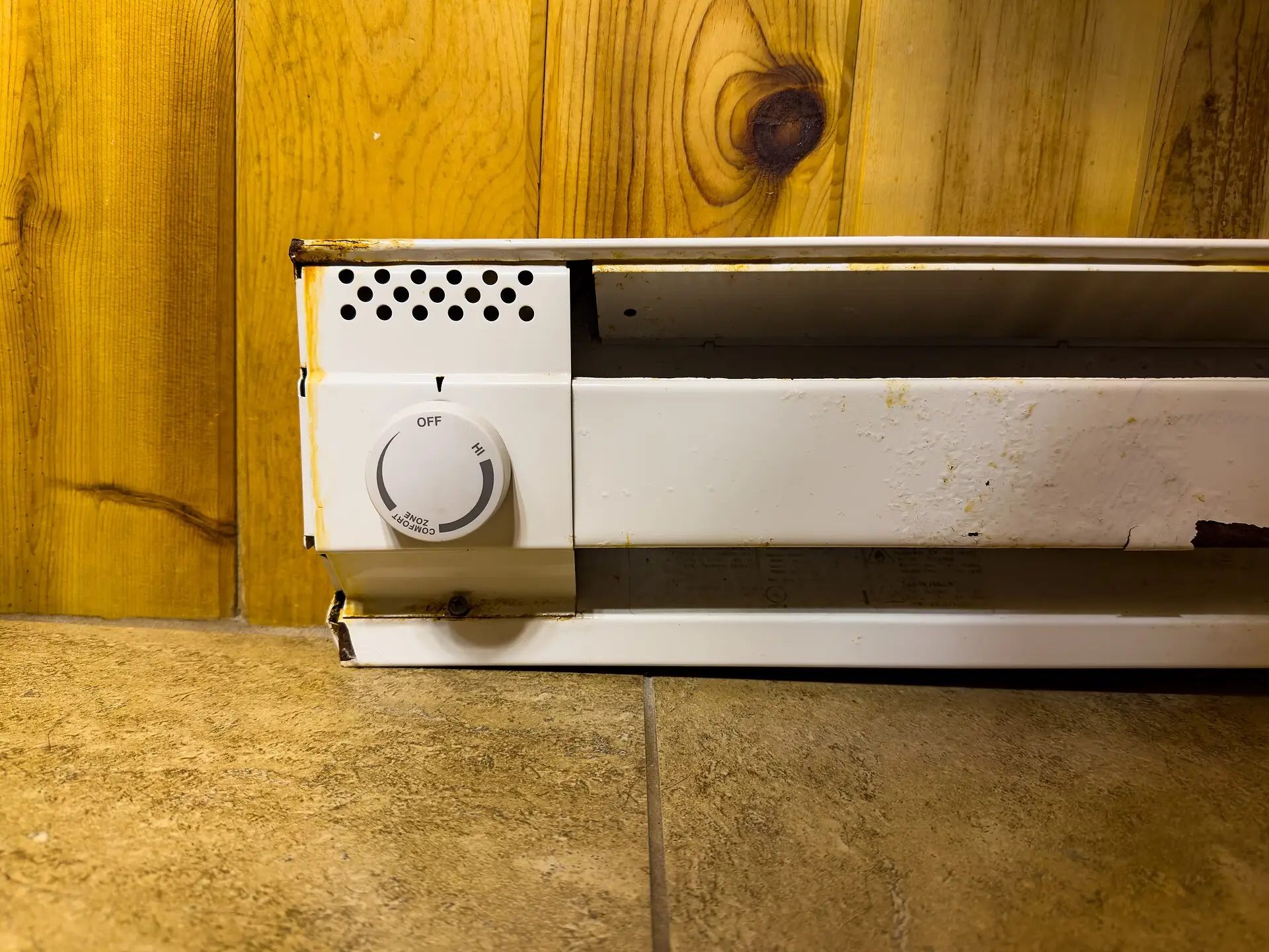 A white electric baseboard heater with a built-in dial thermostat