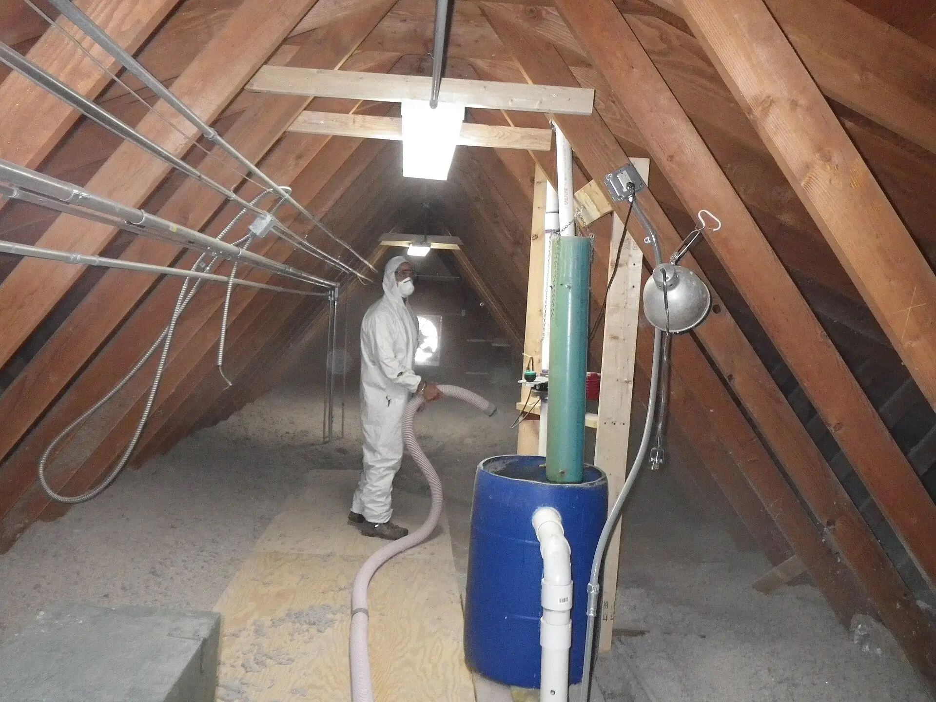 A worker blowing loose-fill insulation into an attic