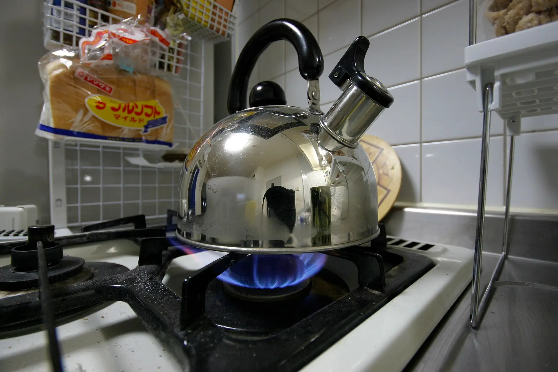 A steel kettle heating on a gas stove burner